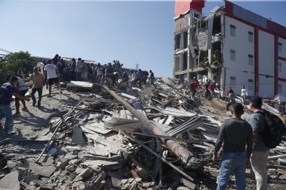 Cali (Colombia), 10/08/2026.- Personas caminan sobre los escombros de un edificio colapsado este lunes